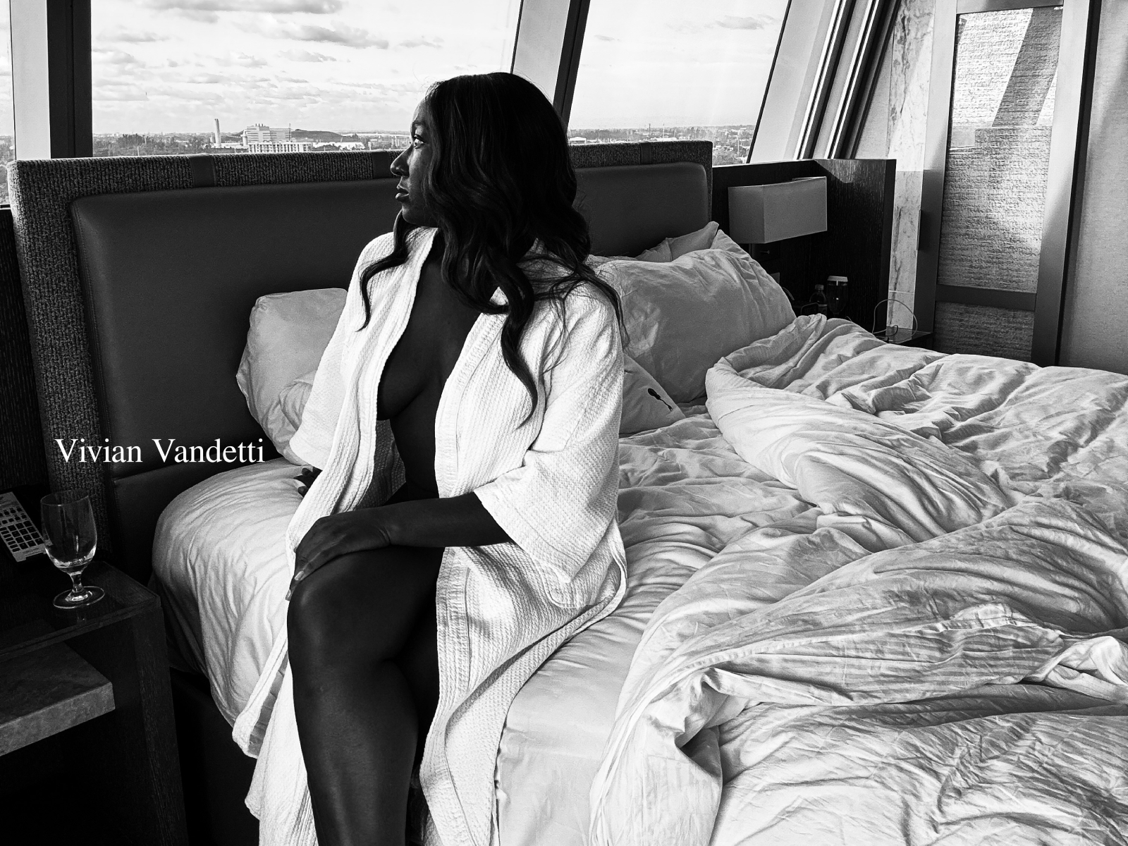 Elegant woman in her 30s gazing out of a penthouse window, reflecting on love and luxury